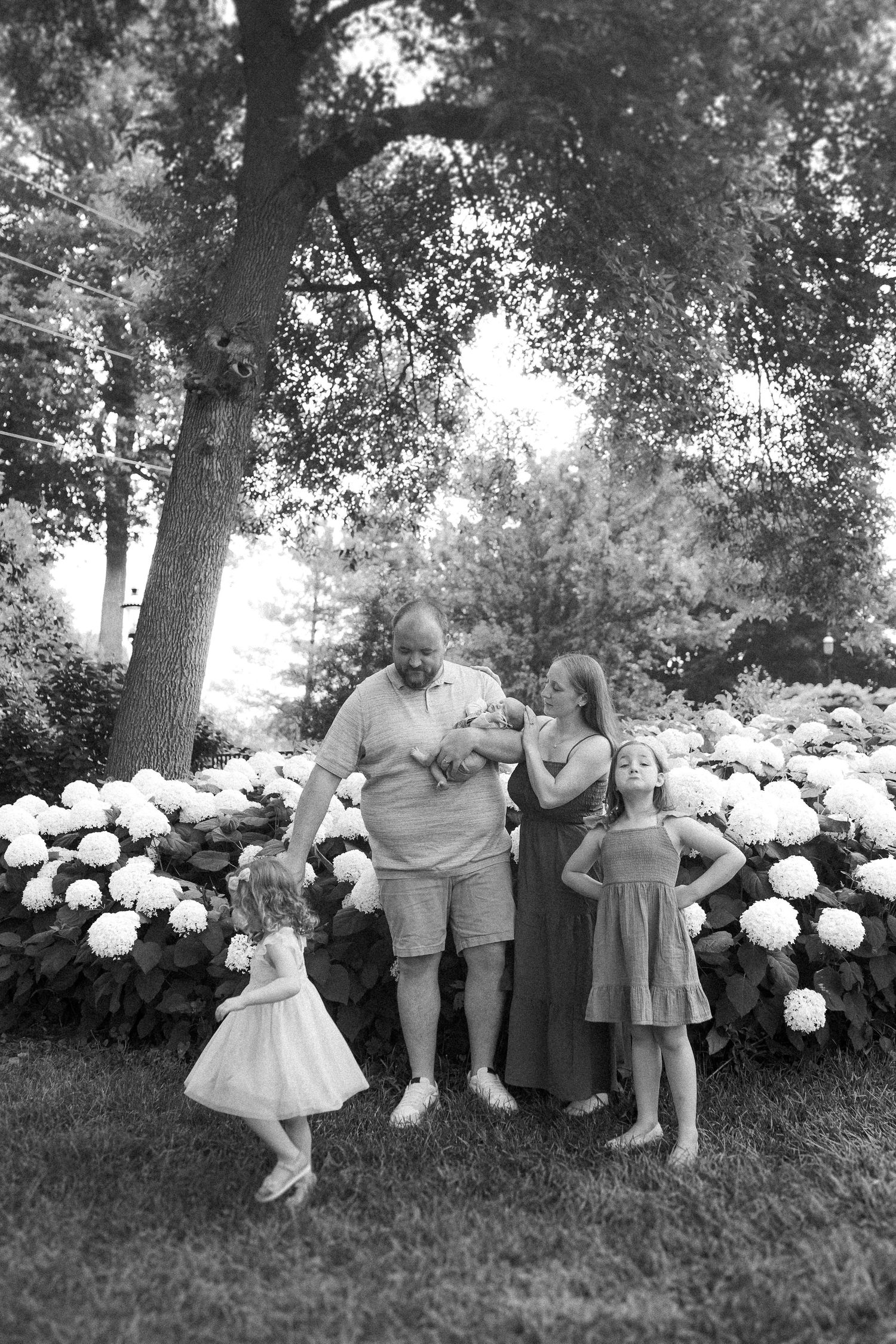 Black and white family portrait with white hydrangea garden backdrop.