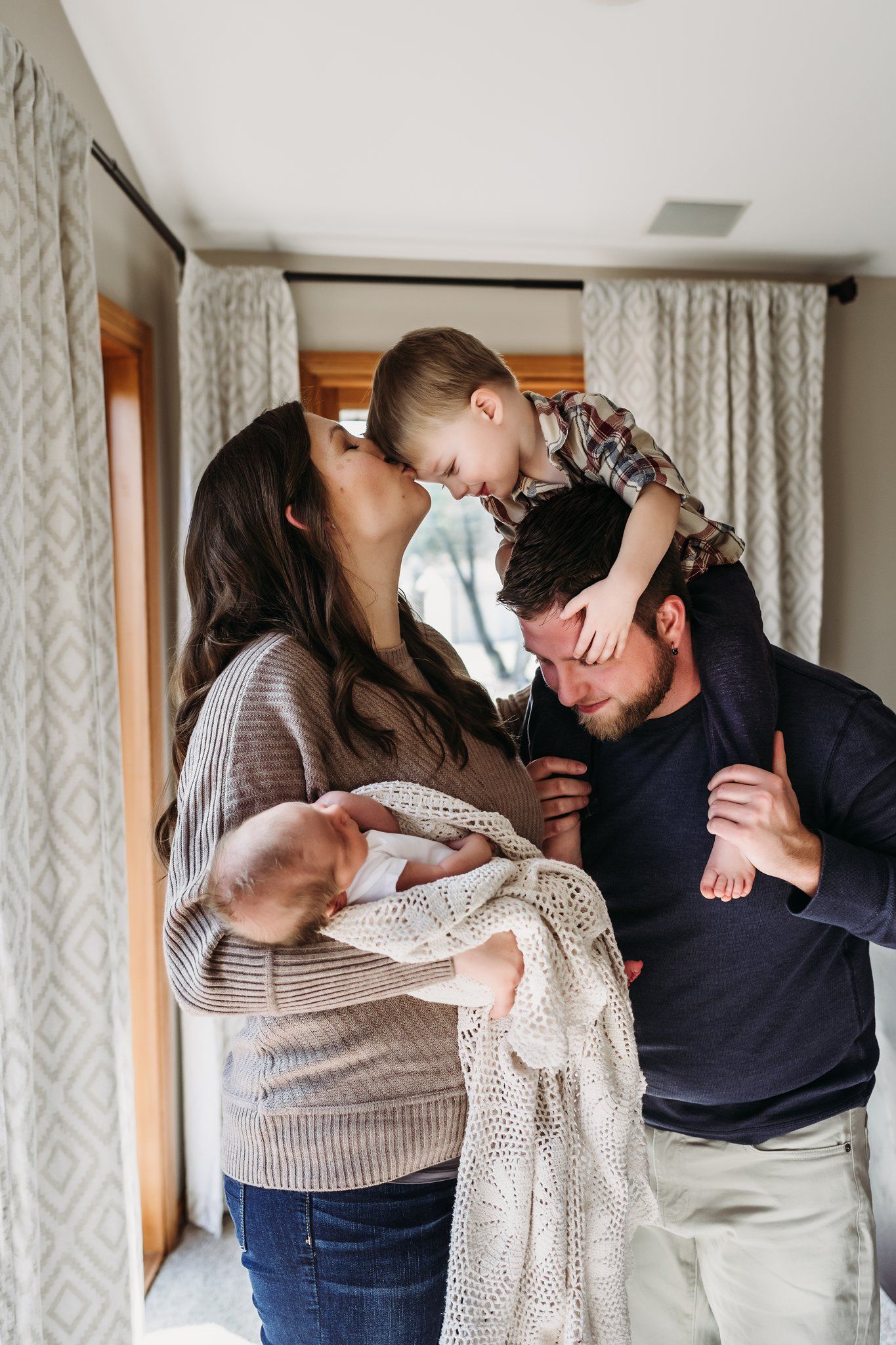 A tender family moment shared between three people embracing while wrapped in a cozy knit blanket.