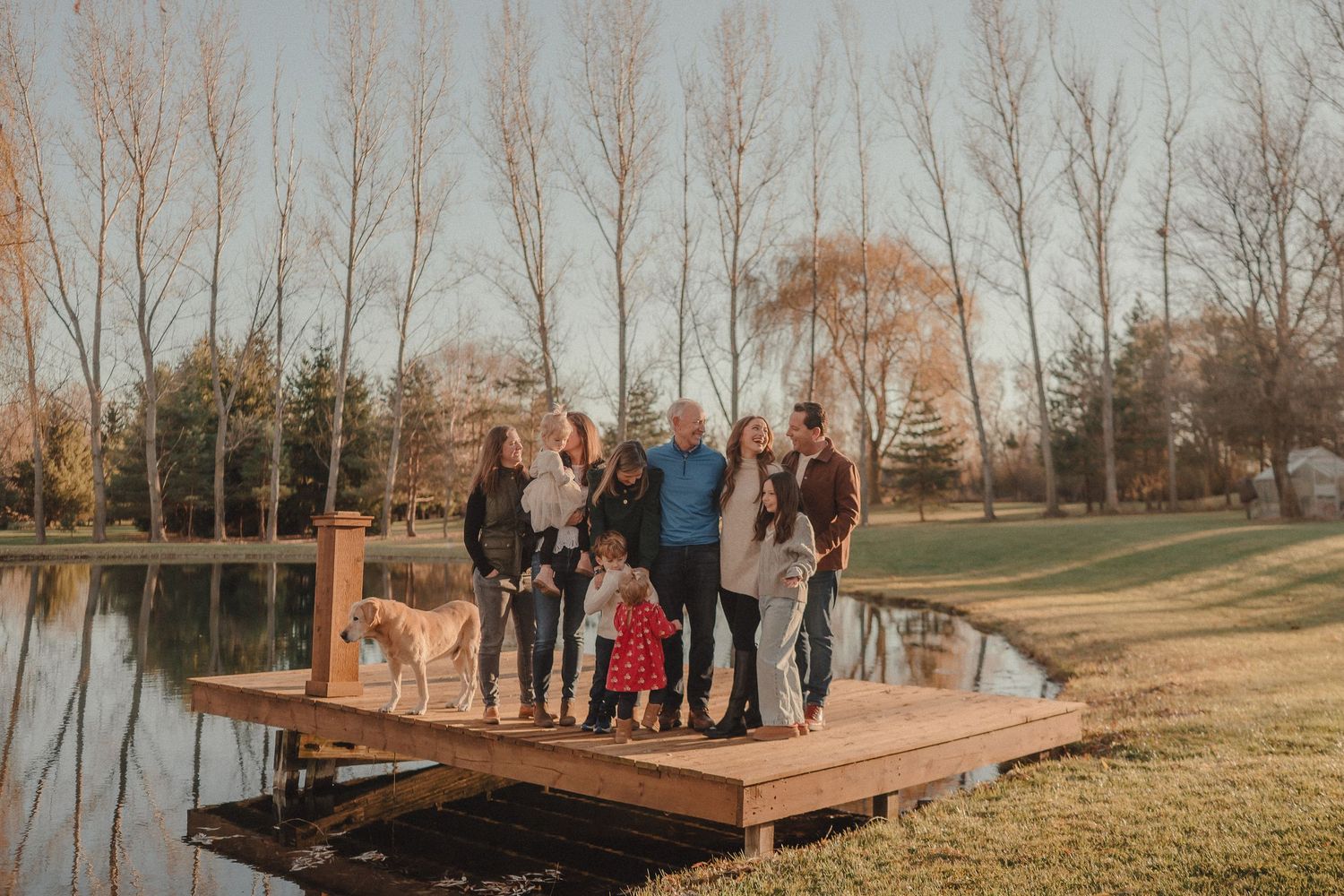 A small group gathers on a wooden deck overlooking a scenic autumn landscape during a special outdoor event.