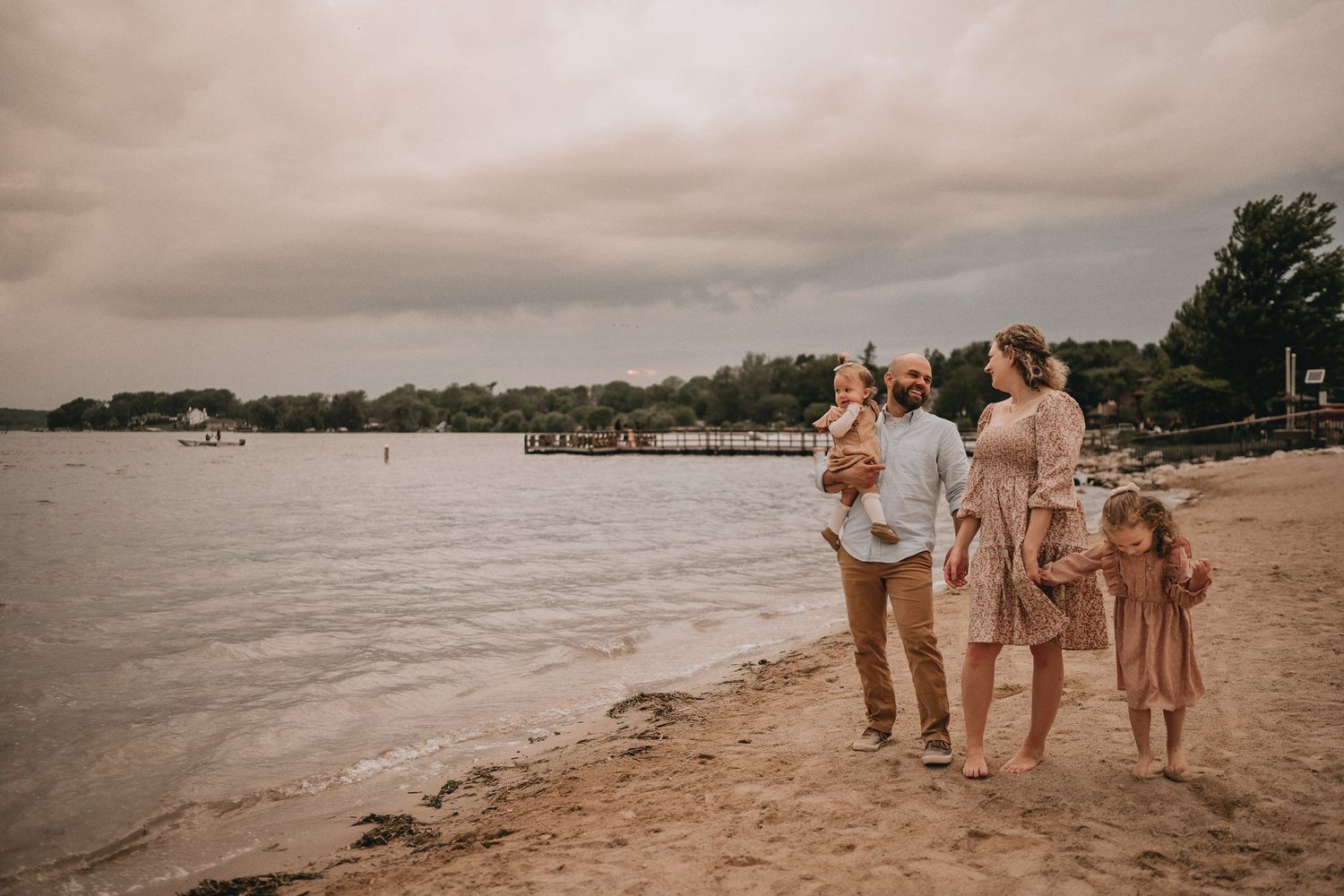 A family standing together on the shoreline during a cloudy evening at the beach.