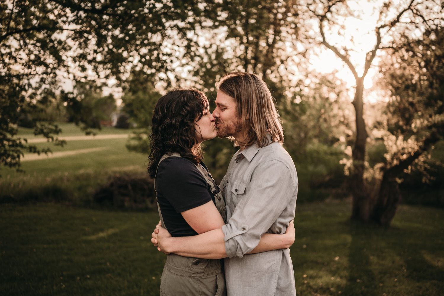 Romantic couple sharing an intimate moment in a park at sunset.