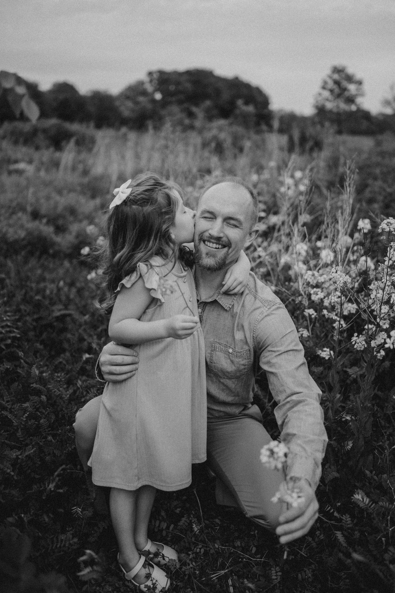 Black and white portrait capturing a playful moment in a blooming wildflower garden.