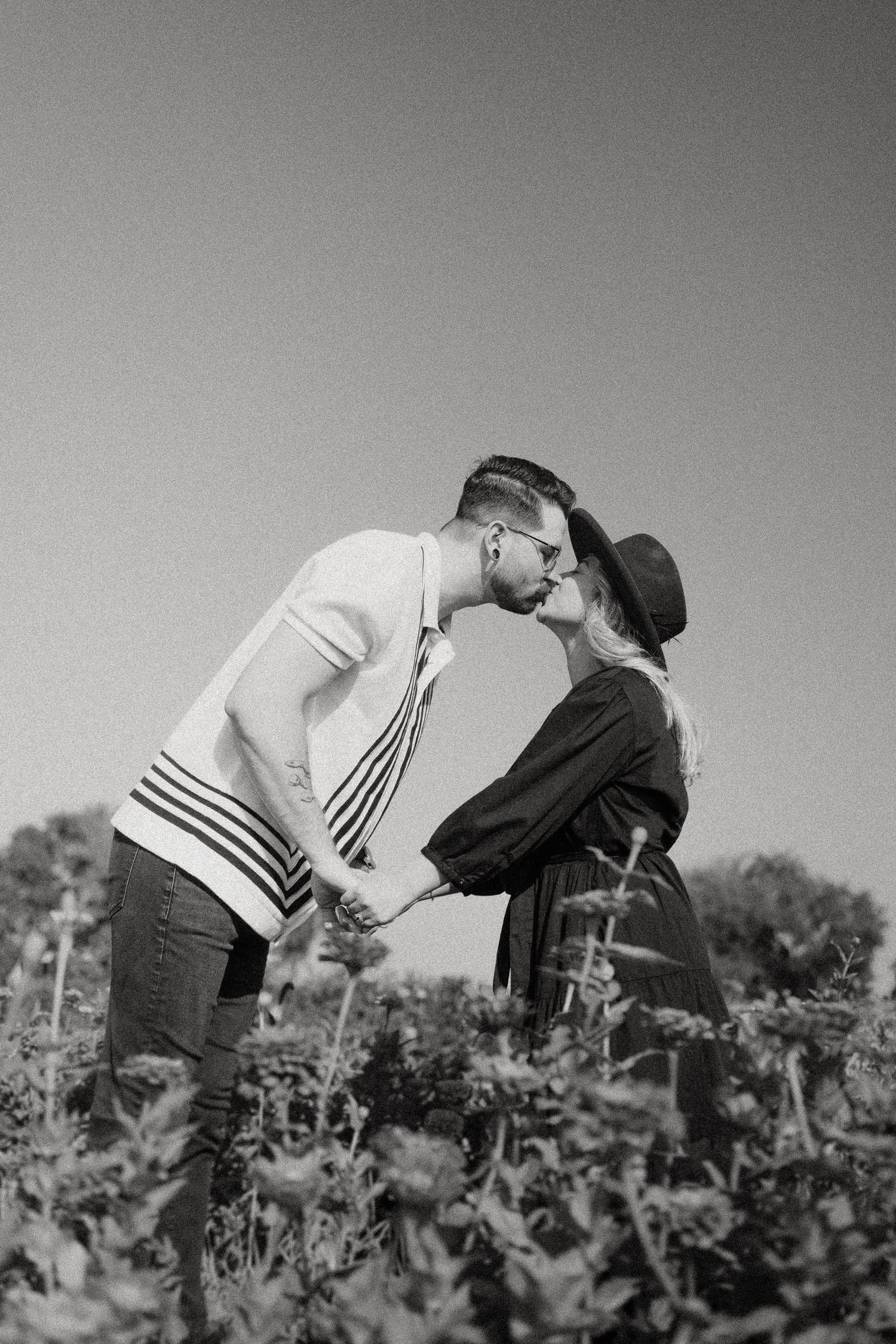 A romantic black and white portrait of a couple embracing in a wildflower field.