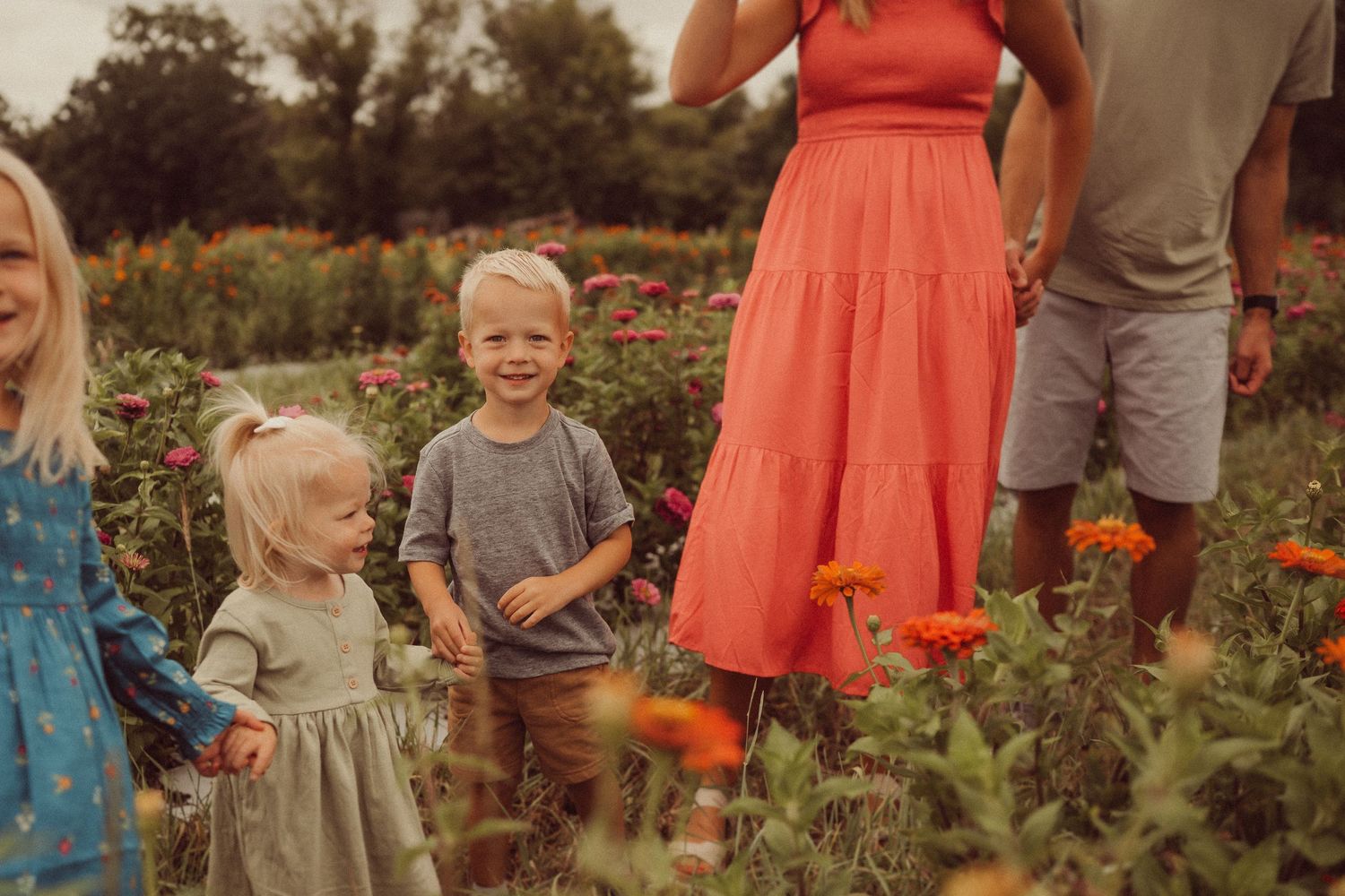 A loving family moment captured among blooming orange flowers in a garden.