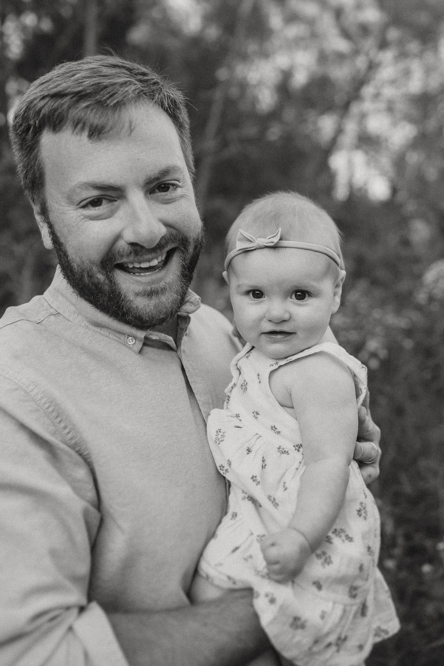 A joyful black and white portrait featuring a small baby in a floral dress.