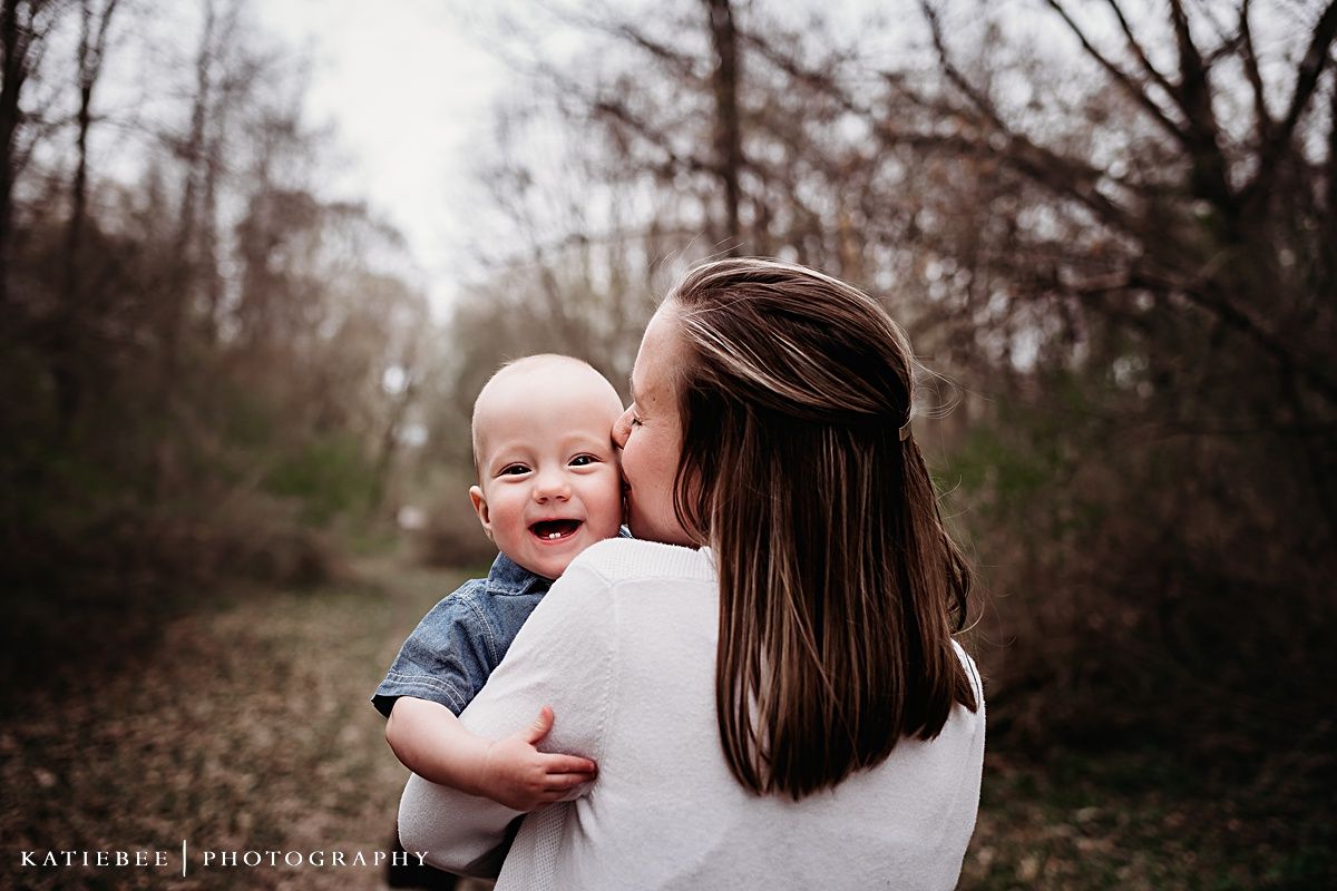 Sweet embrace captured on nature trail with autumn trees in background.