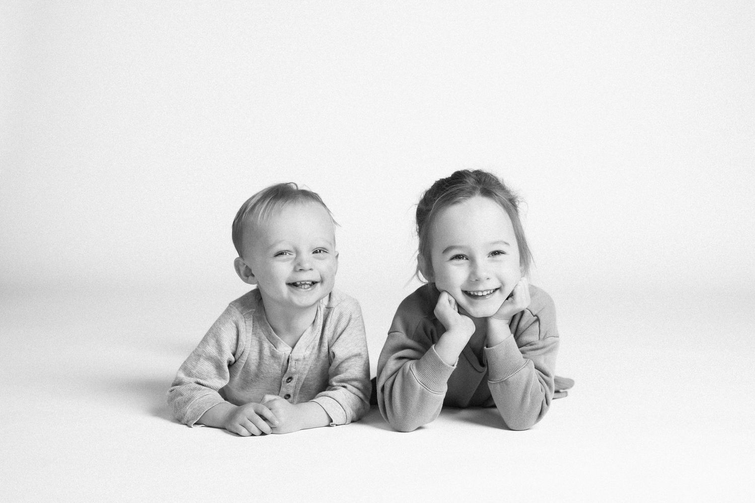 Five black and white portraits of infants lying on their stomachs showing developmental stages and milestones.
