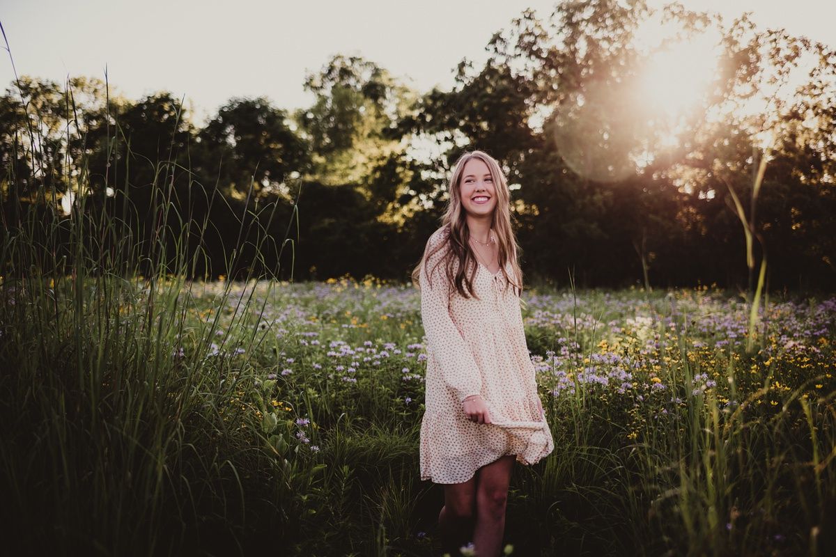 Sunset portrait in a wildflower field wearing a flowing cream-colored dress.
