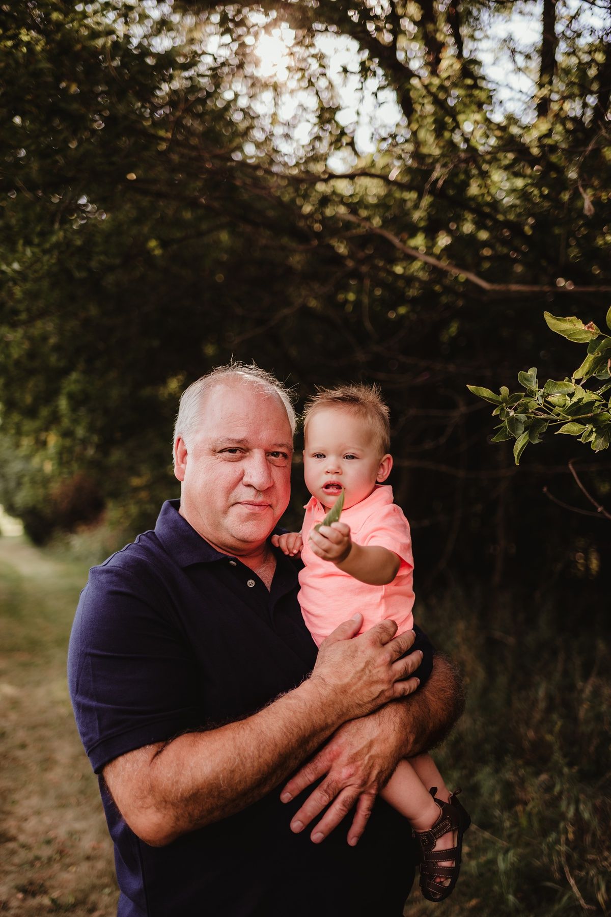 A tender outdoor portrait showcasing an intergenerational embrace in a natural setting at sunset.