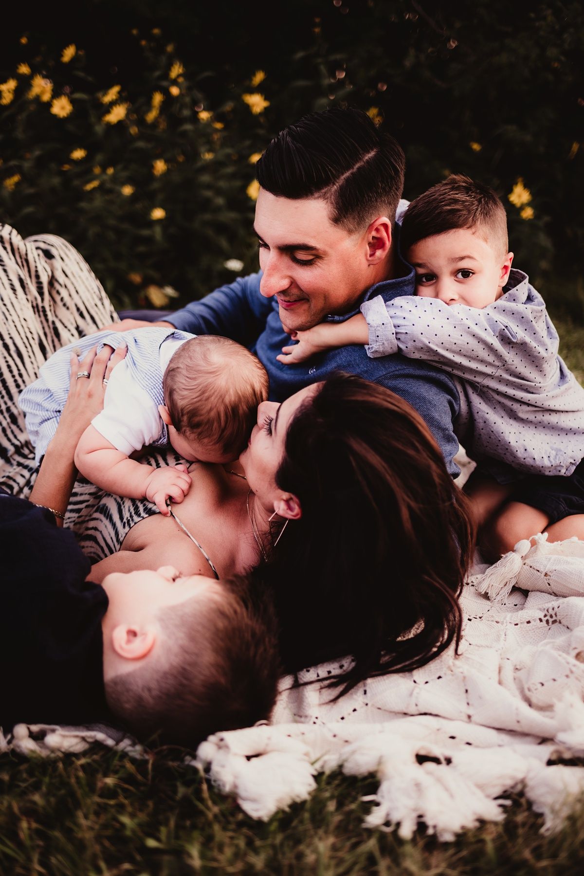 Intimate family moment captured on white blanket during outdoor photo session.