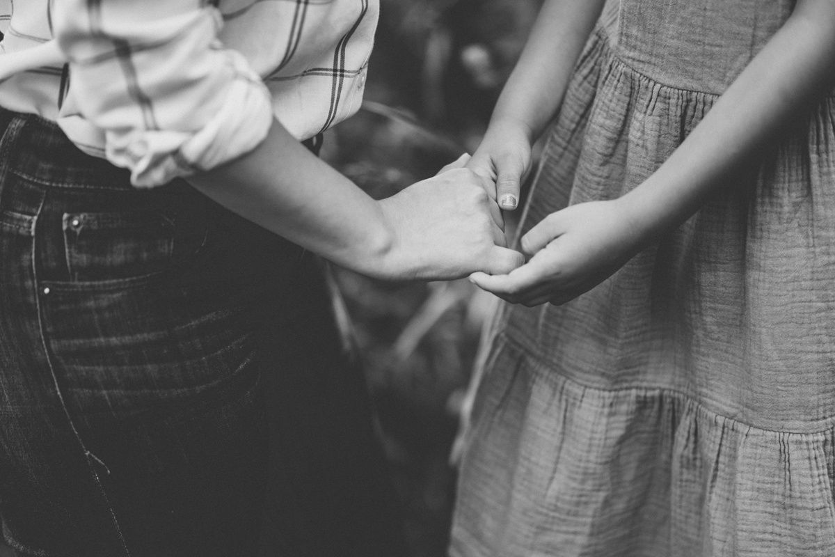 Black and white detail shot of hands holding together in tender moment.