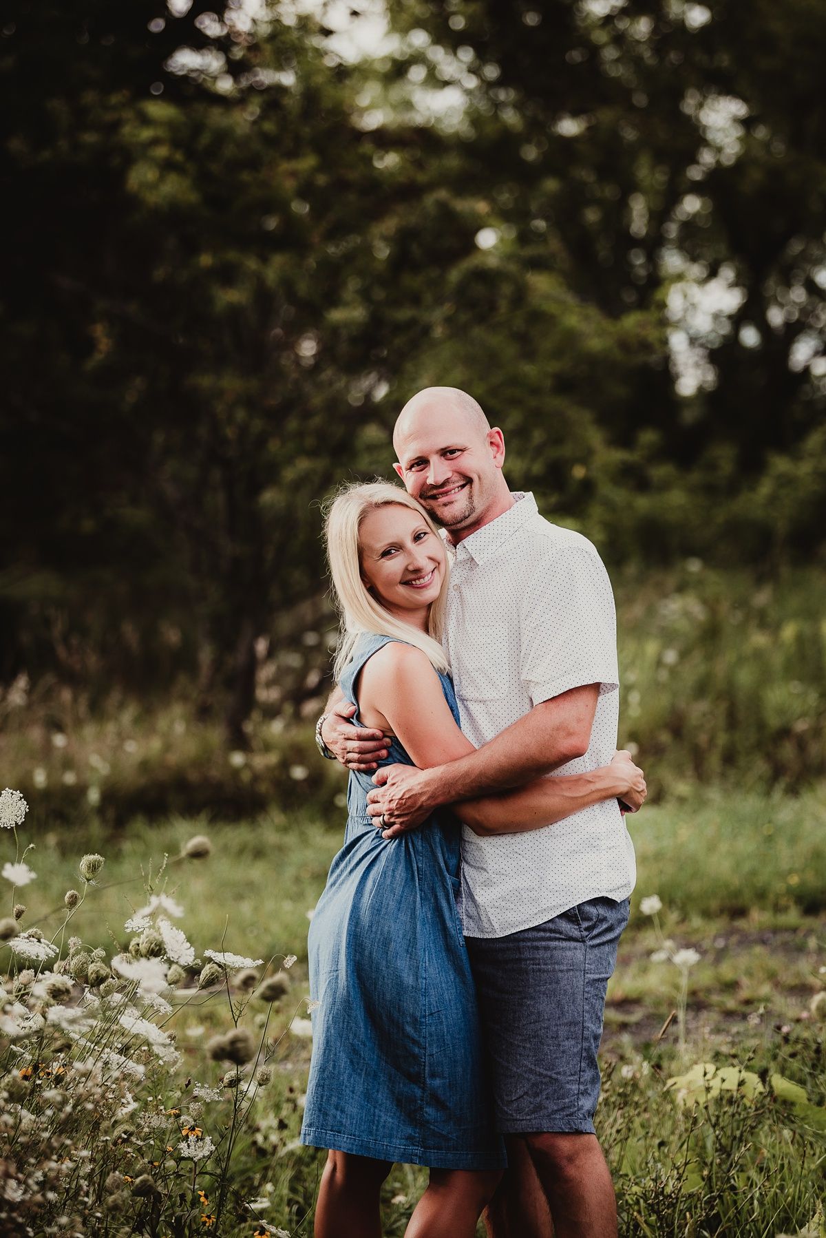 Romantic couple embracing and smiling together in a meadow filled with wildflowers.