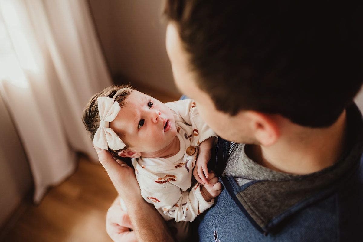 Close-up of a baby wearing a floral headband being held tenderly.