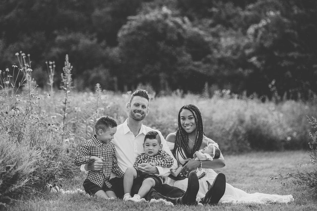 Black and white family portrait in a natural outdoor setting.