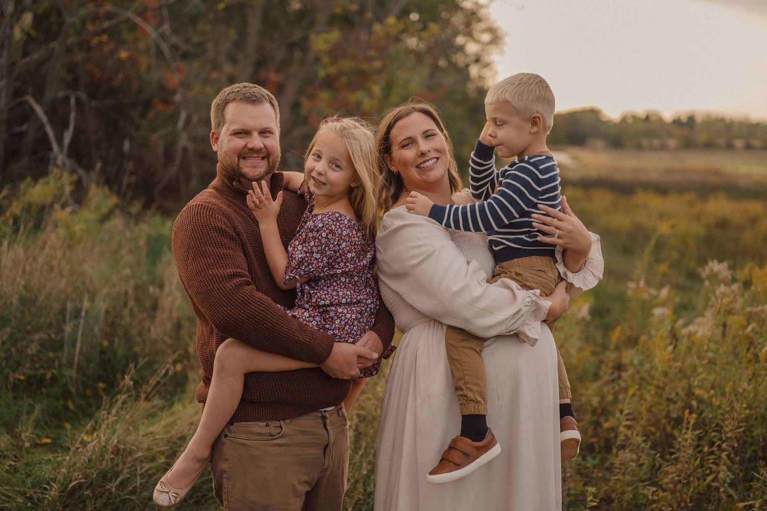 A family shares joyful moments together in a natural outdoor setting during golden hour.