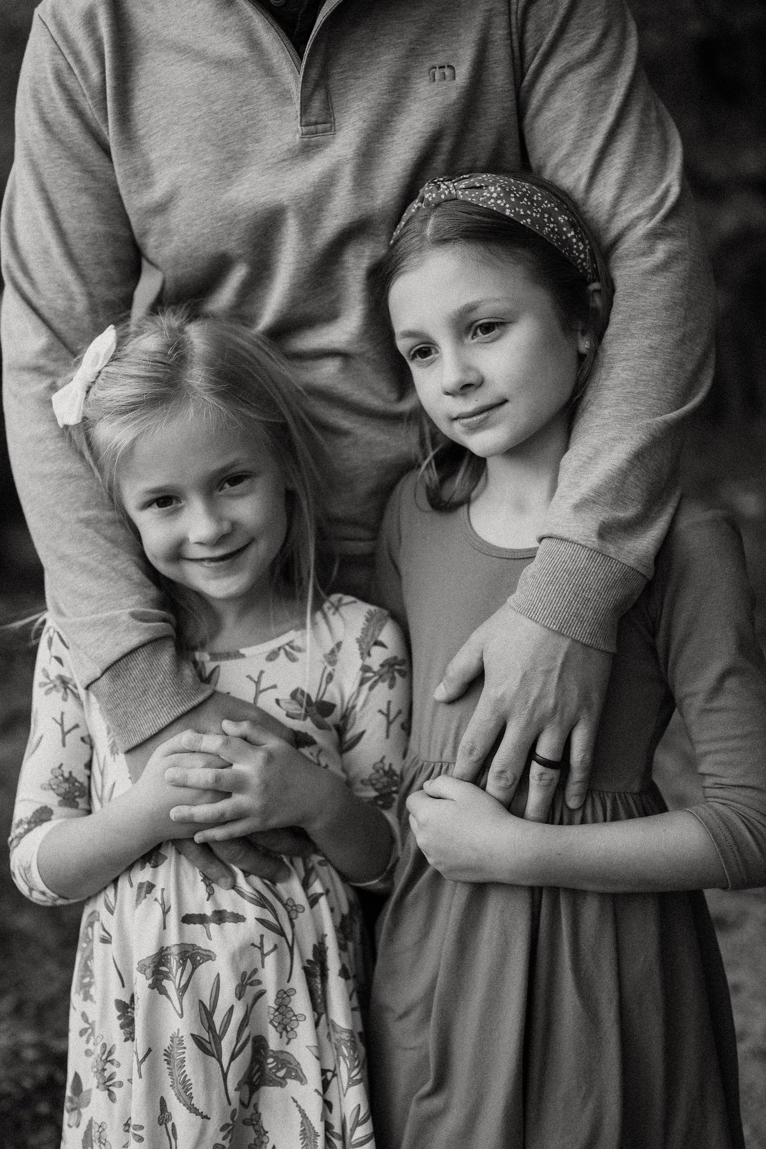 Black and white portrait showing close family embrace in casual attire.