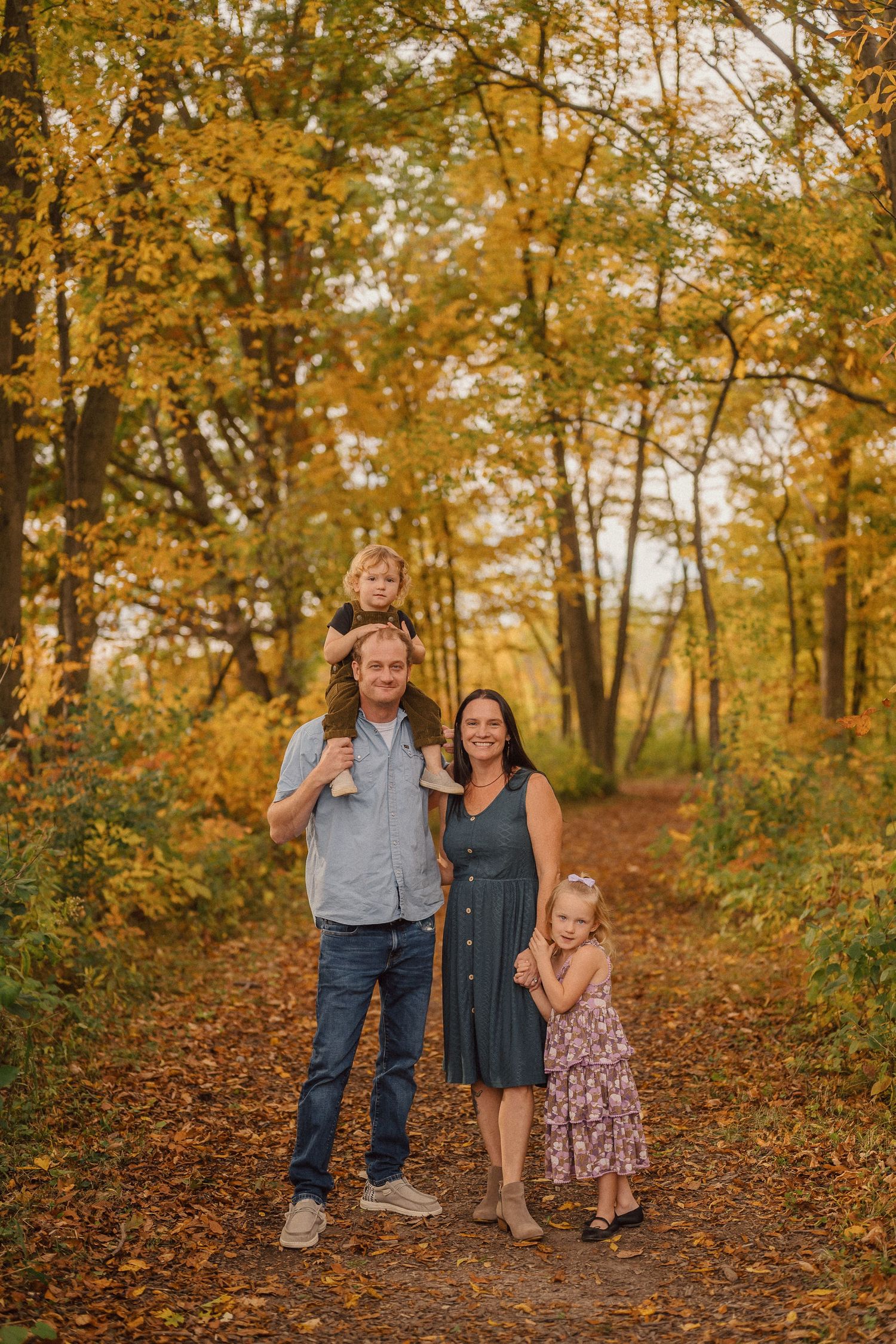 Family enjoying an autumn walk together on a trail surrounded by golden fall foliage.