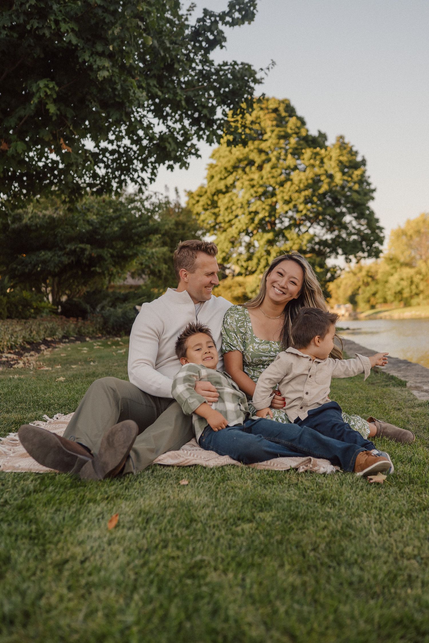 A family relaxes together on green grass during a warm afternoon in the park.