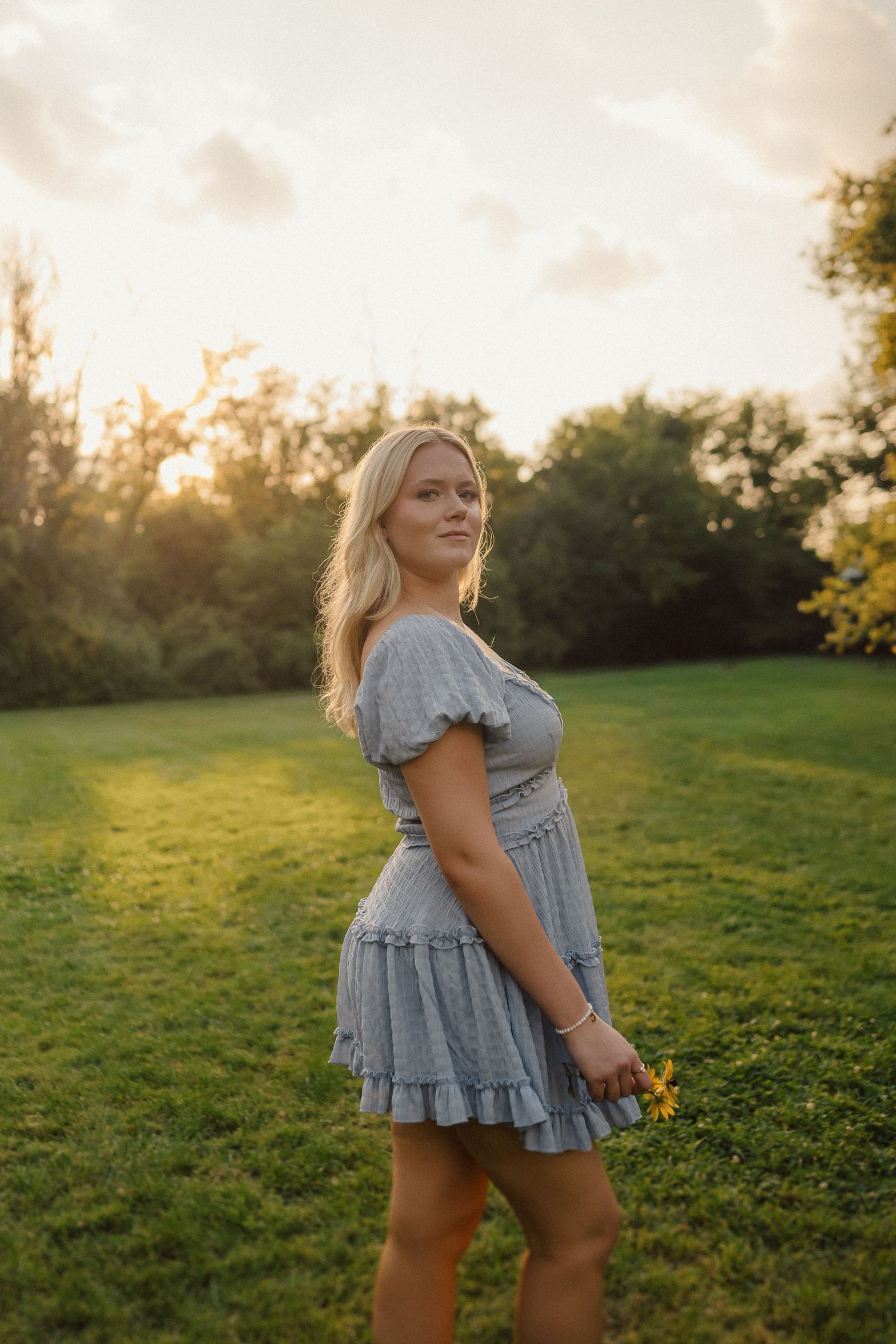 A candid series of photos showing a person in a gray dress walking through a sunlit meadow at golden hour.