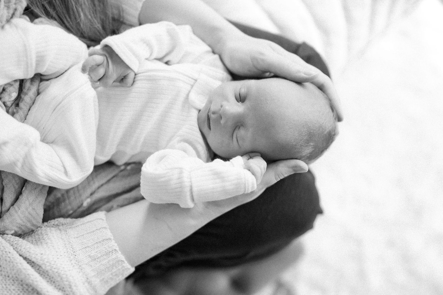 Close-up view of gently holding a newborn baby's tiny feet in adult hands.