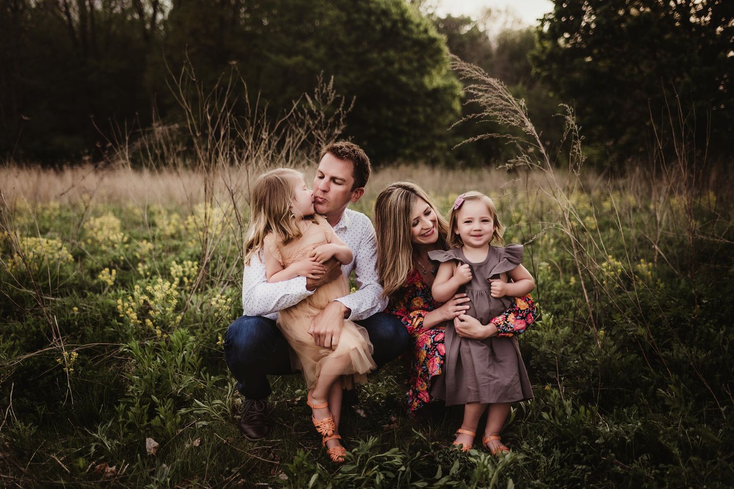 Family gathering on grassy hill during golden hour surrounded by natural landscape.