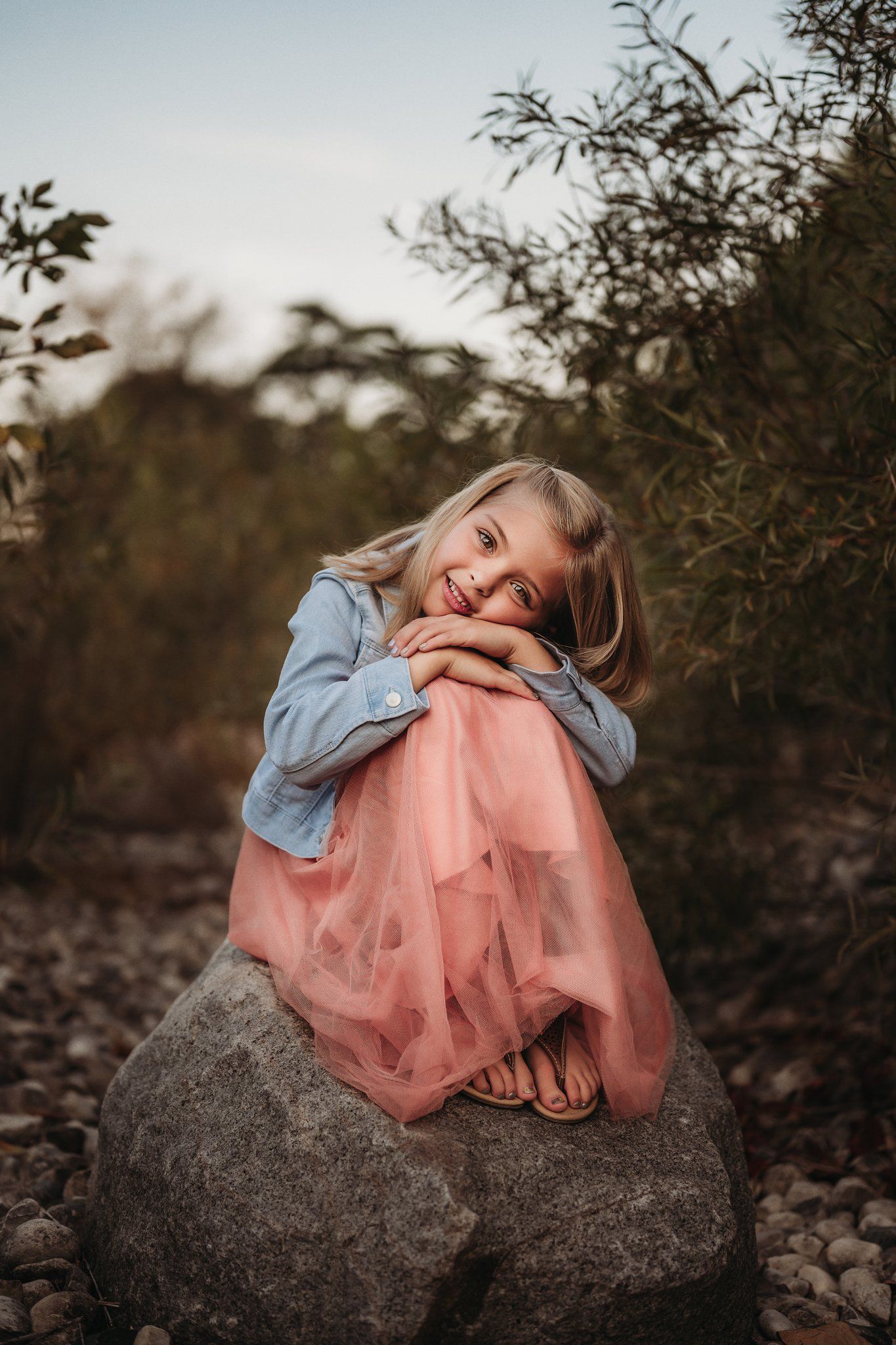 A playful pose captured on a rocky perch during a sunset outdoor photoshoot.