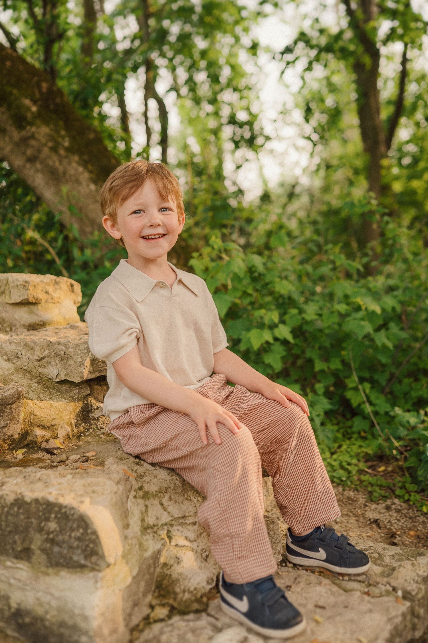 A candid portrait taken on stone steps with natural greenery in the background.