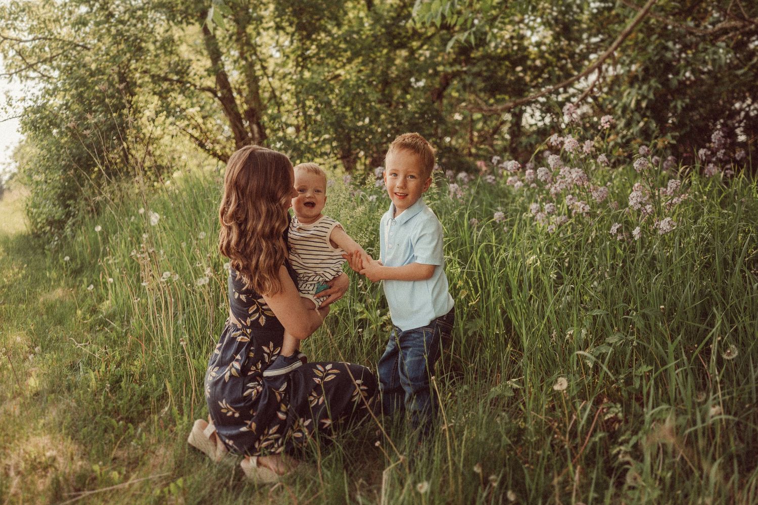 Family sharing joyful moment together in tall grass during golden hour.