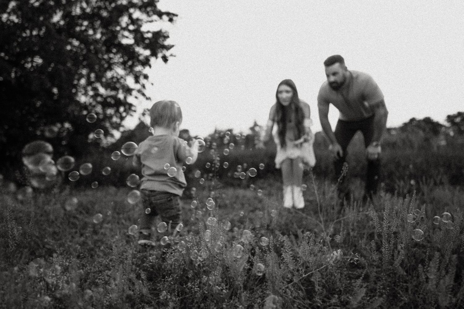 Black and white capture of a family playing together in a meadow.