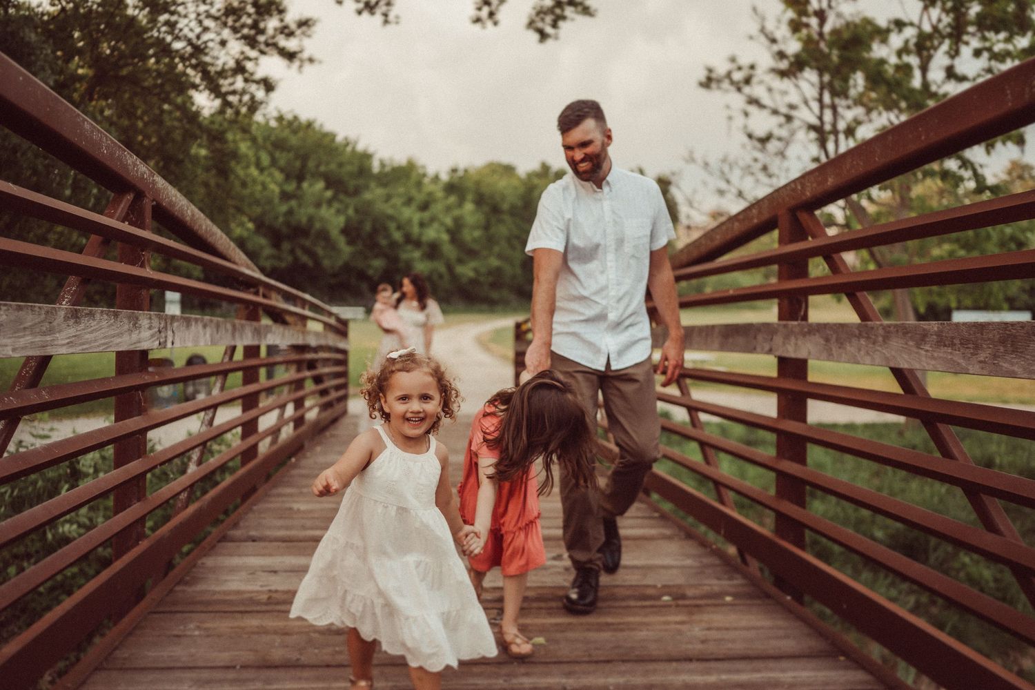 A playful family moment captured on a wooden bridge outdoors.