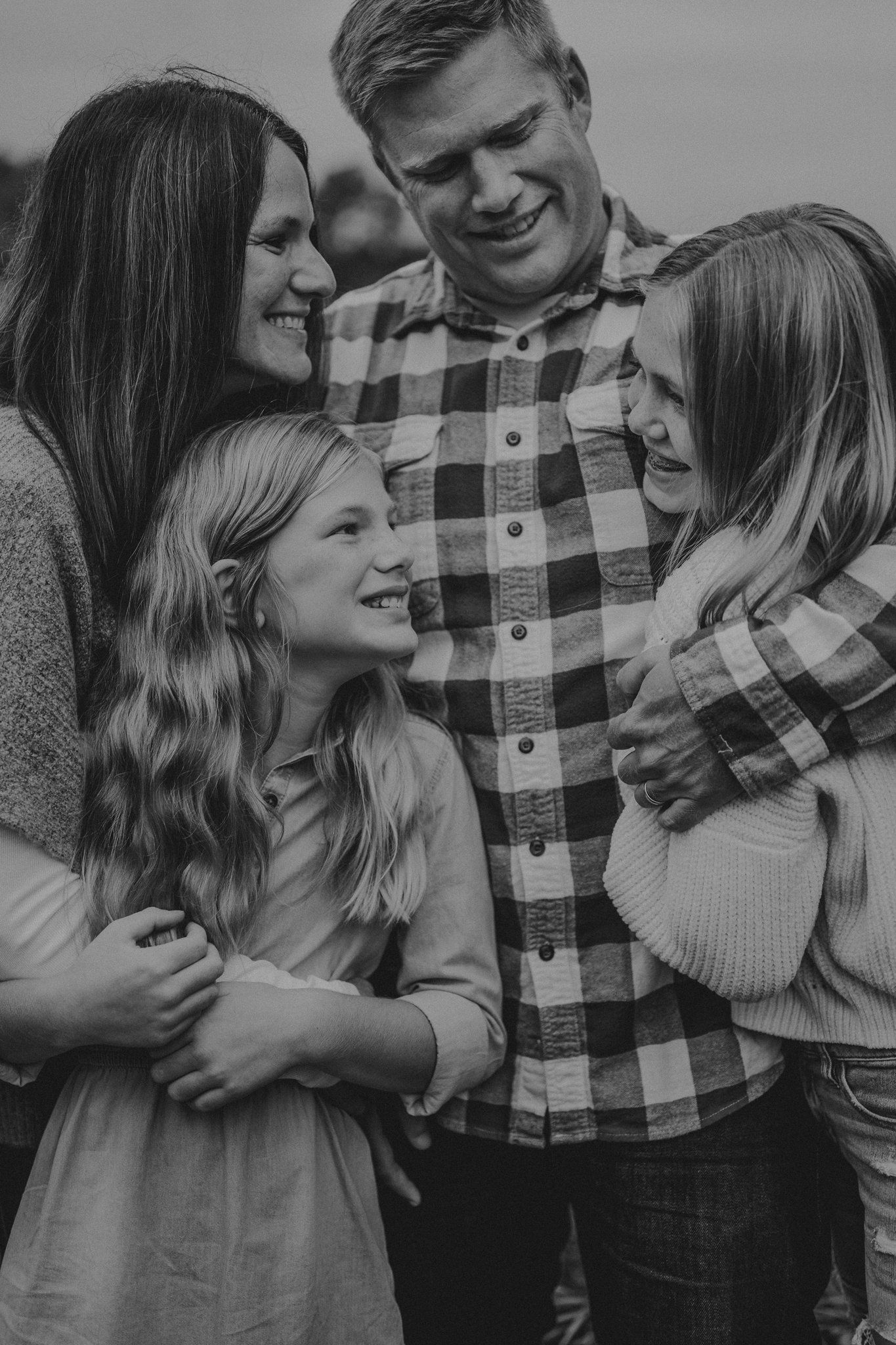 A loving family shares joyful laughter together in black and white portrait.
