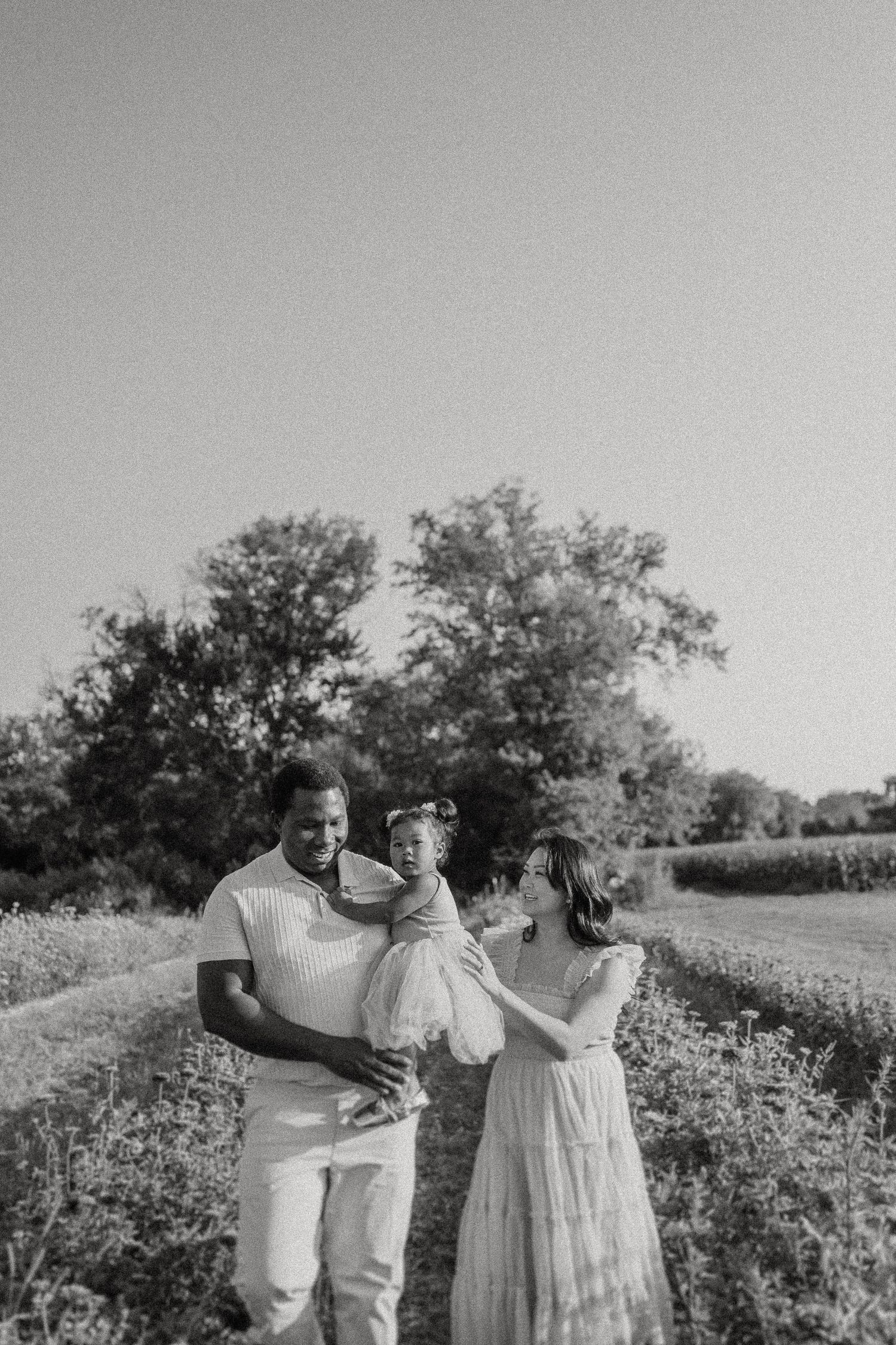 A family sharing an intimate moment in a wildflower field captured in black and white.