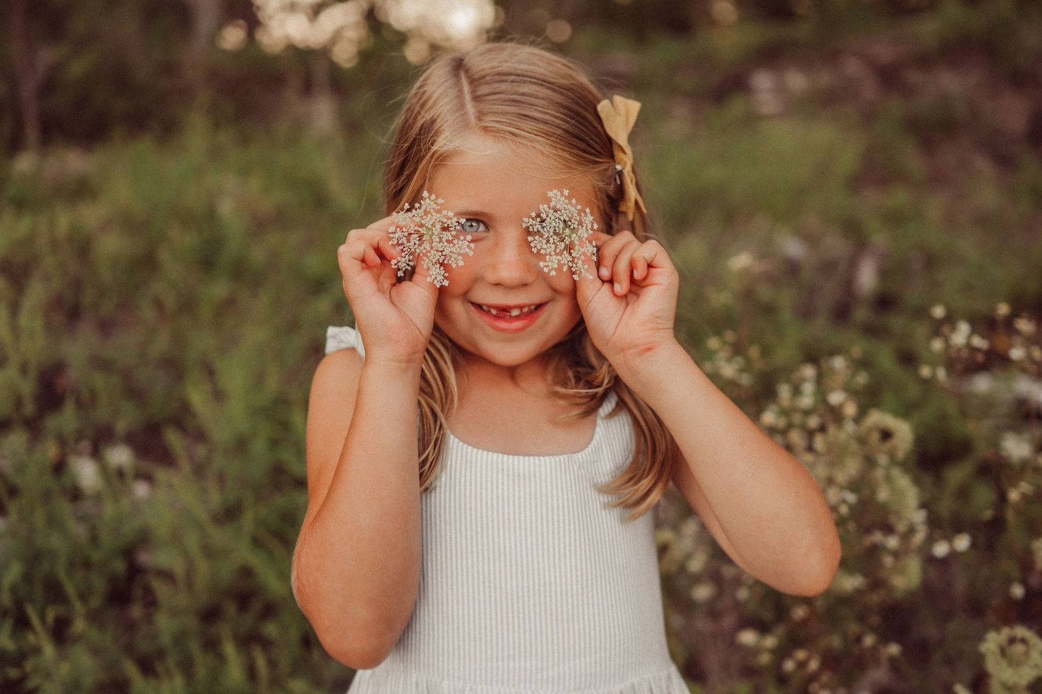 A playful moment captured with wildflowers held up to eyes in a summer garden.