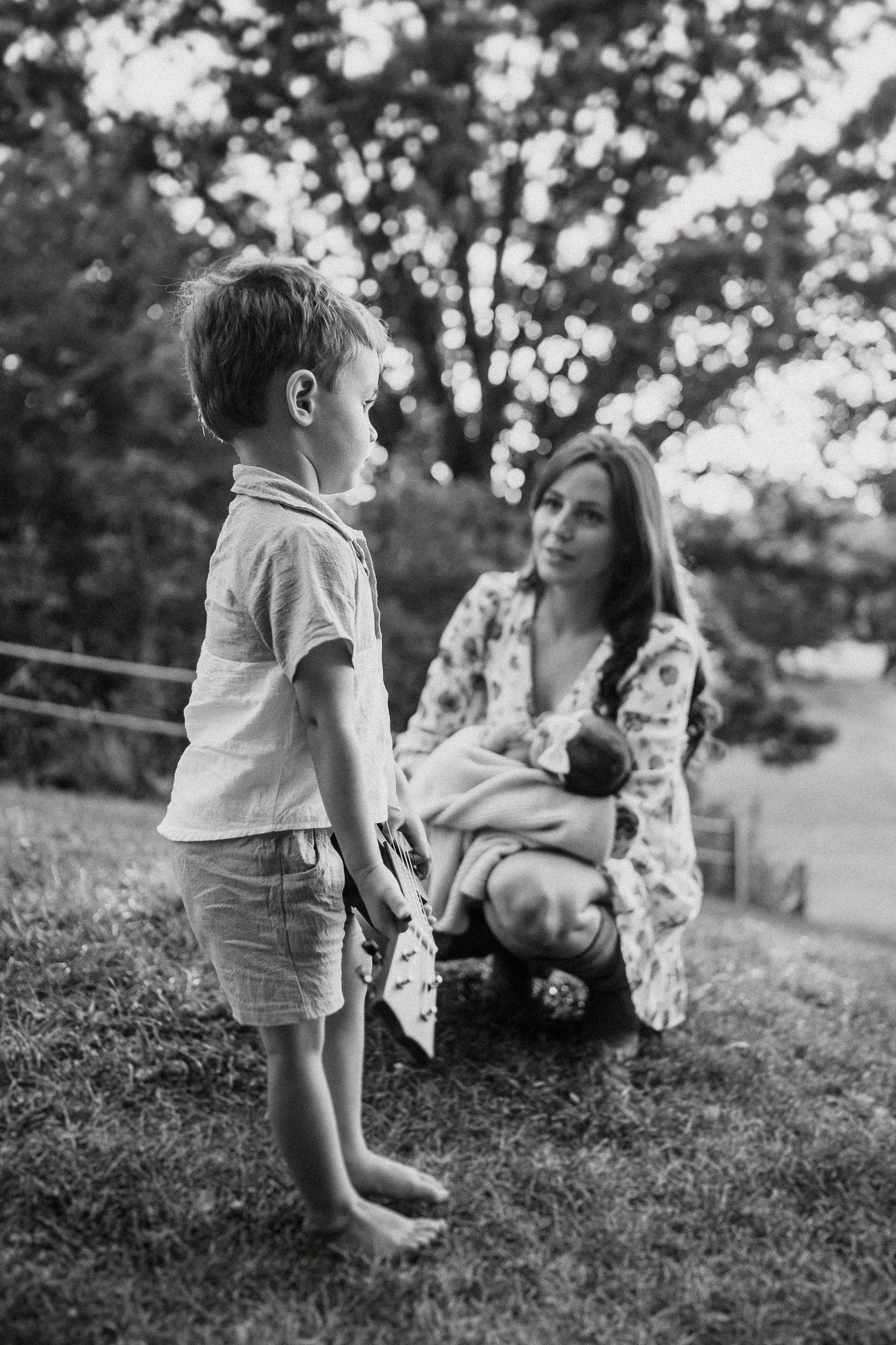 Black and white portrait of family moment on a grassy hillside.