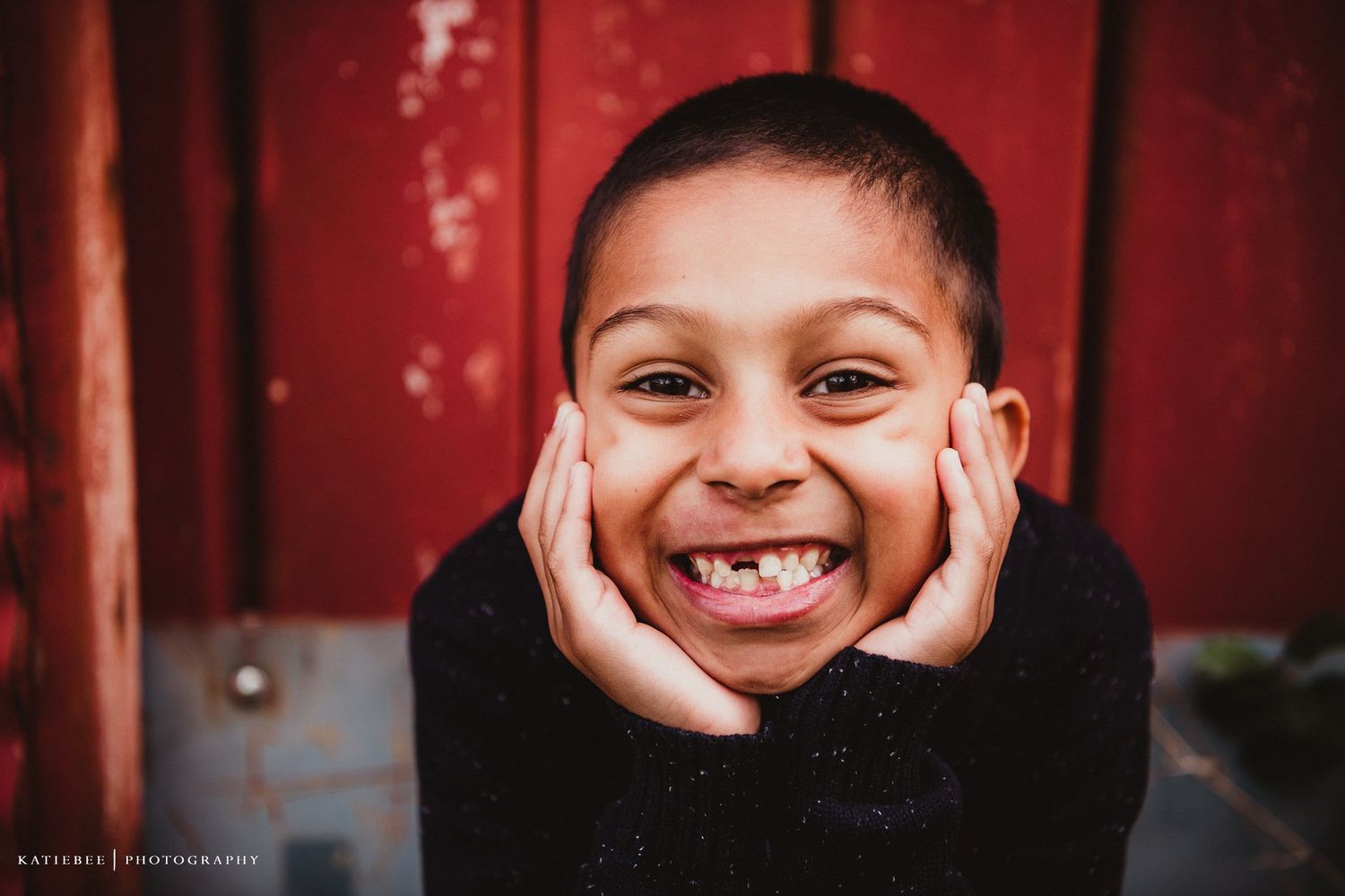 Close up portrait of an energetic smile against a red barn wall background.