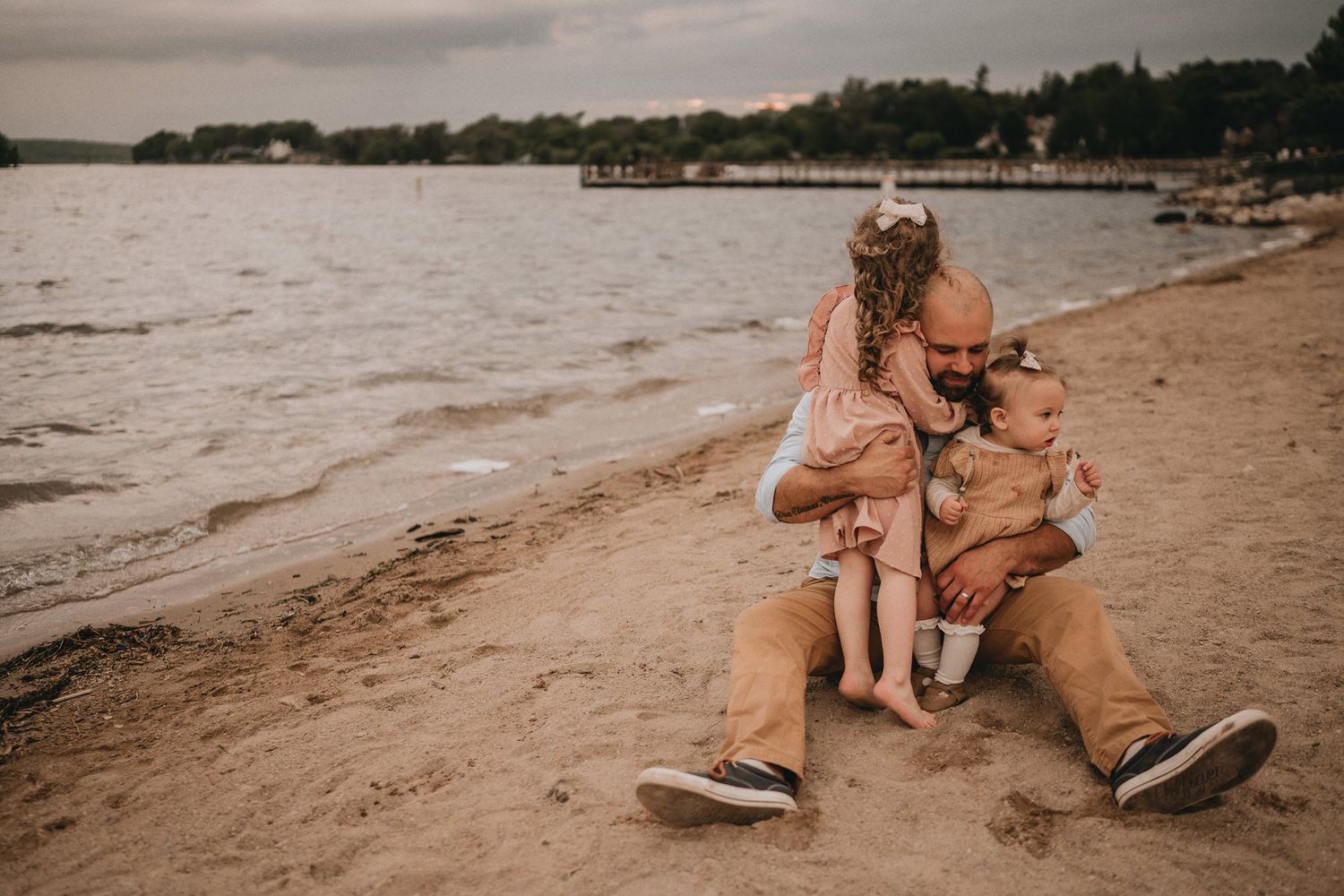 A heartwarming moment between family members sitting together on a beach at sunset.