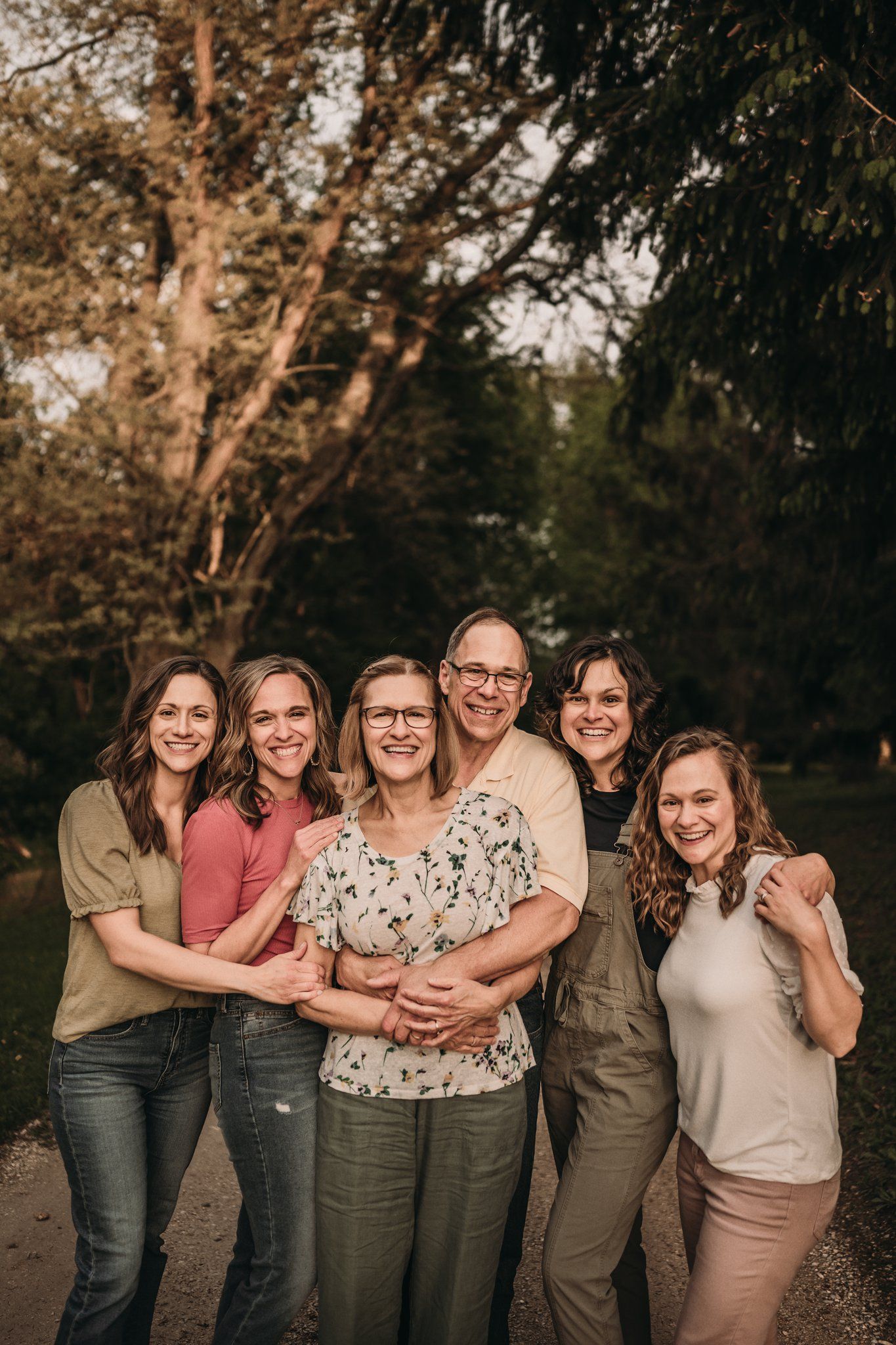 A group stands close together outdoors smiling warmly in coordinated casual attire.