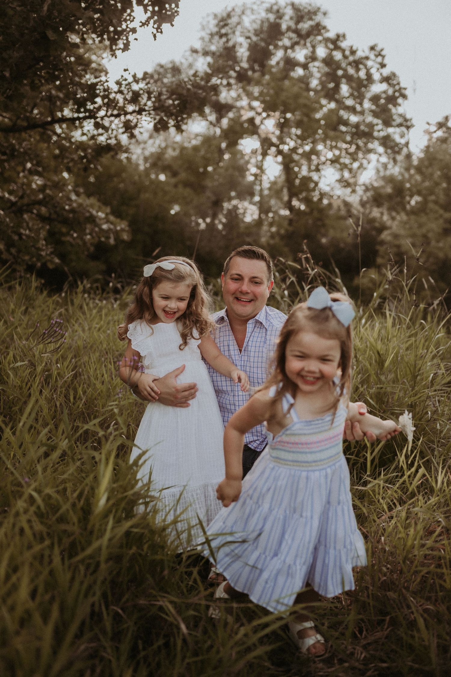 Joyful family moment captured in a field with everyone wearing coordinating outfits.
