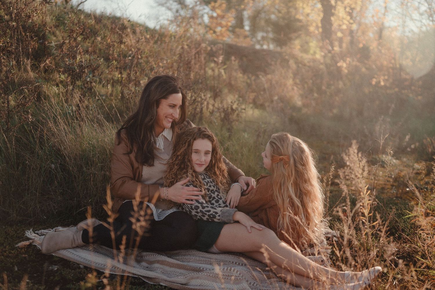 Golden hour family photoshoot with sun flare and autumn scenery.