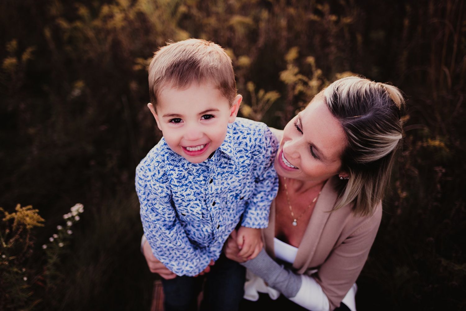 A joyful outdoor portrait session in tall grass during golden hour.