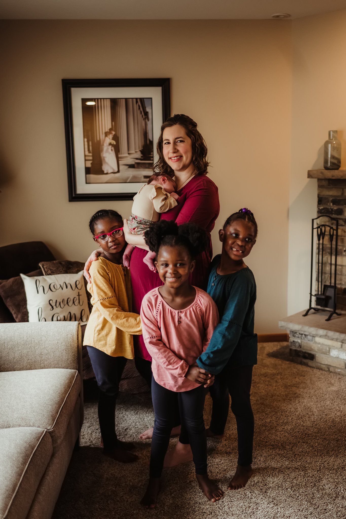 A joyful group poses together in a living room while holding a newborn baby.