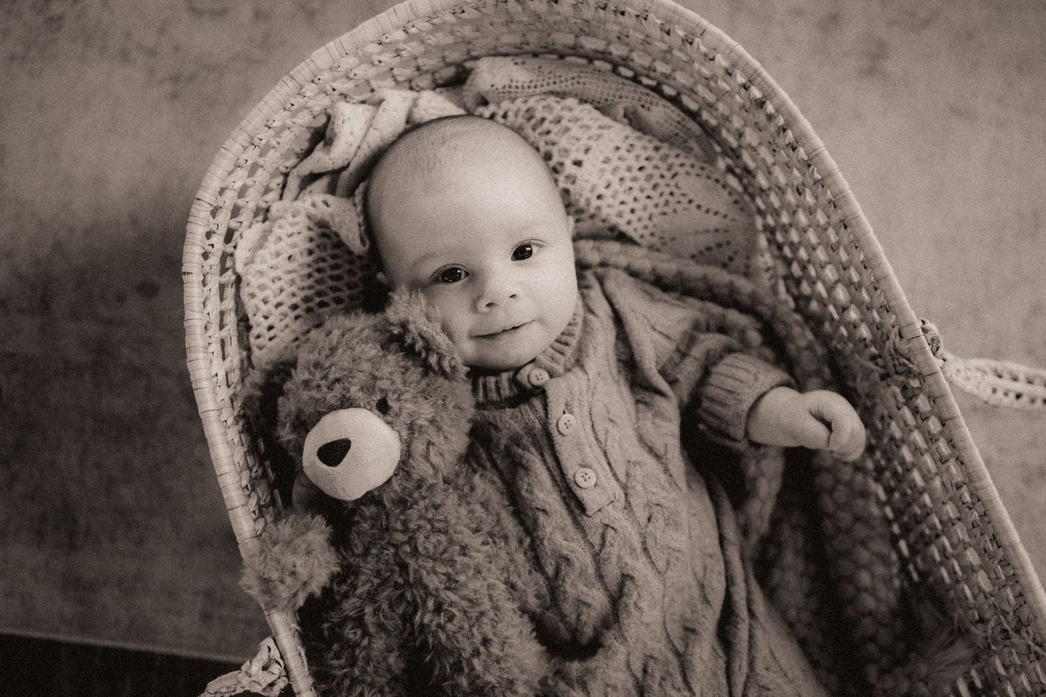 Black and white series of a baby nestled in soft textured blankets and knit materials.