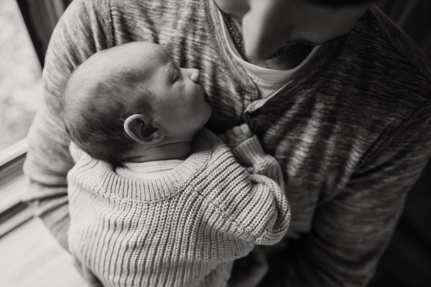 Close-up black and white photo of siblings bonding in soft sweaters.