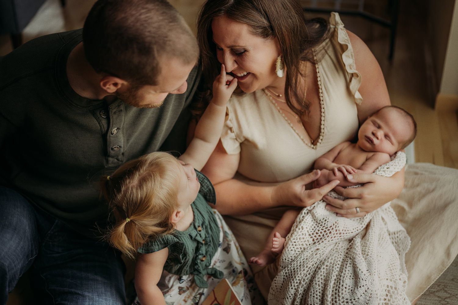 Family shares an intimate moment together on a couch with a baby and knit blanket.