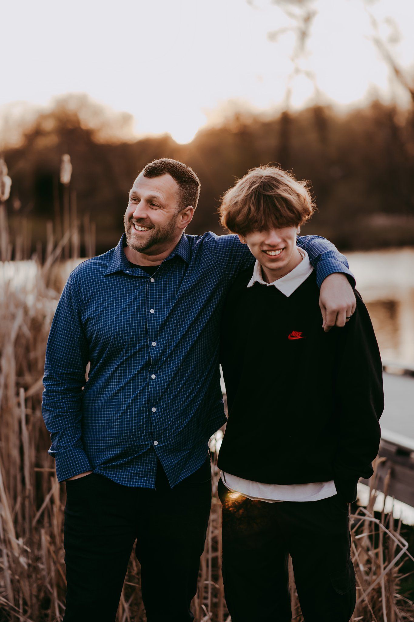 Two people share a laugh together by waterfront during sunset.