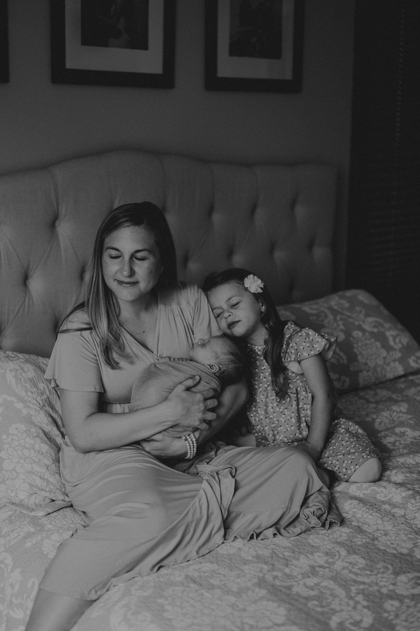 Black and white intimate family portrait captured on plush bedding.