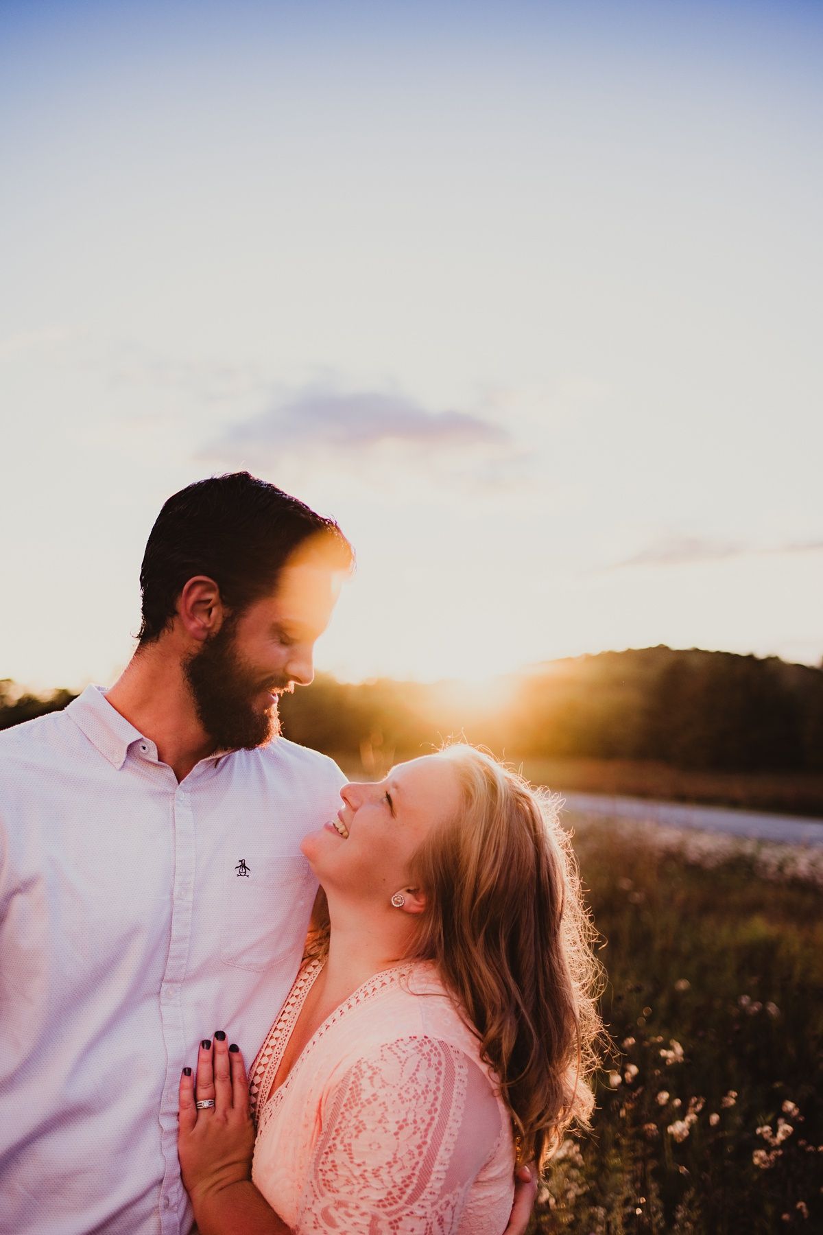 Golden sunset illuminates a romantic couple's portrait in a summer meadow.