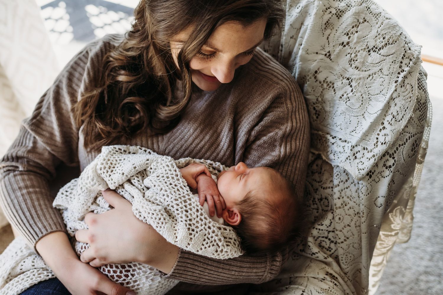 A tender moment between parent and infant swaddled in a knitted blanket on a relaxed afternoon.