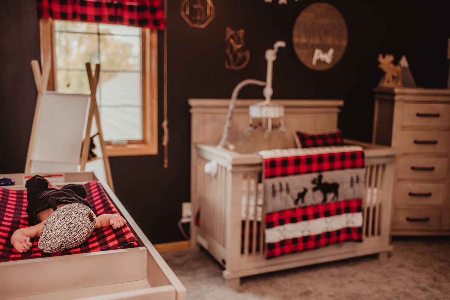 Rustic nursery decorated with buffalo plaid accents featuring a white crib and woodland themed decor.