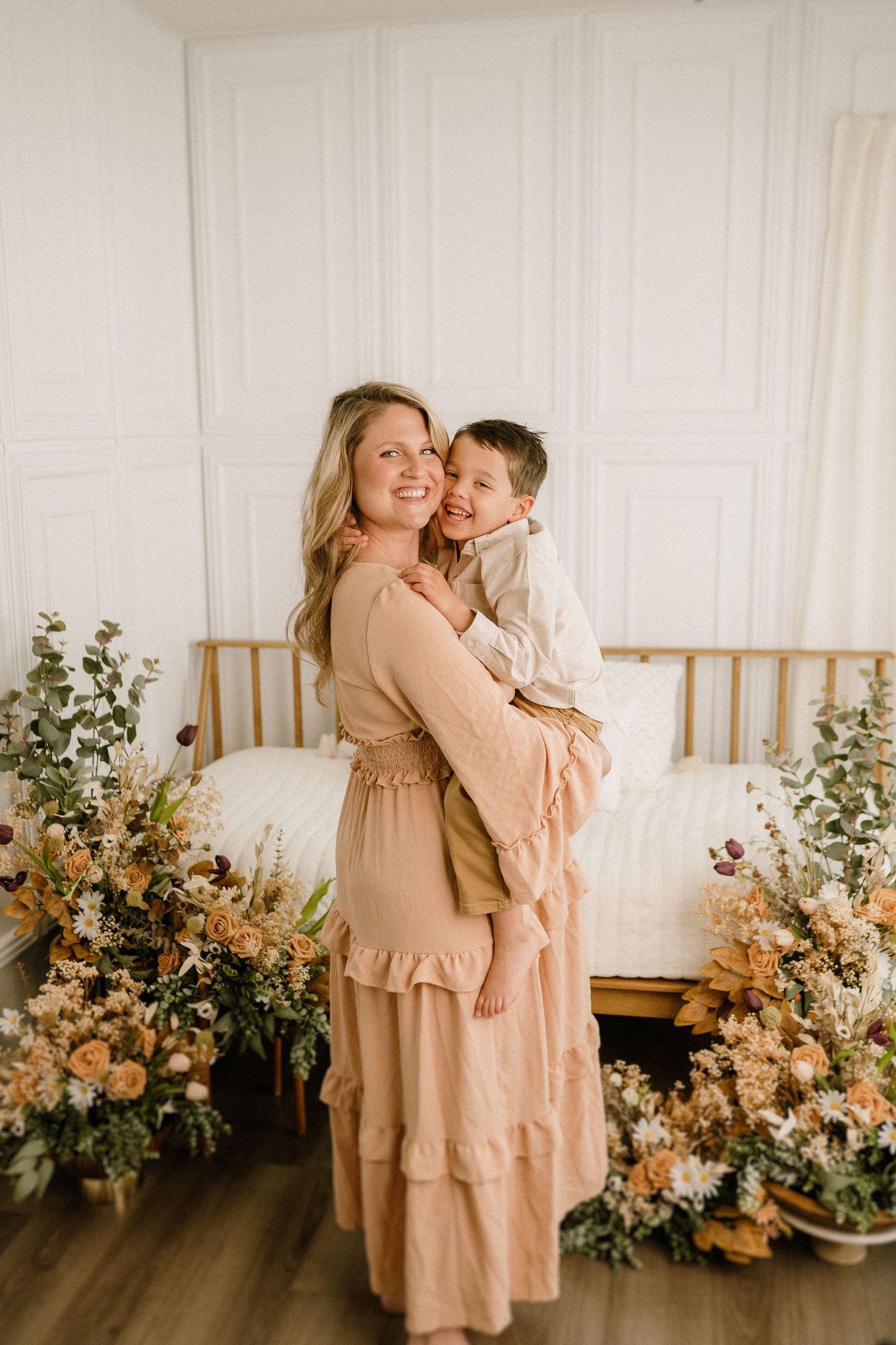 A joyful moment captured between parent and child hugging and laughing in a room decorated with peach florals.